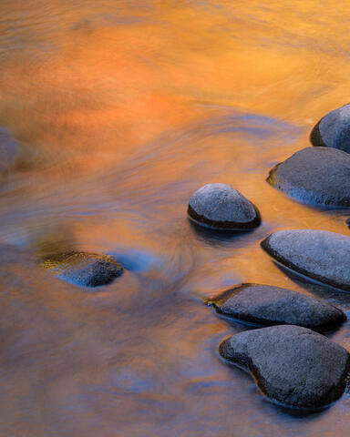 Abstract fine art photograph of flowing Appalachian water and river stones with warm autumn color by Joseph Rossbach.
