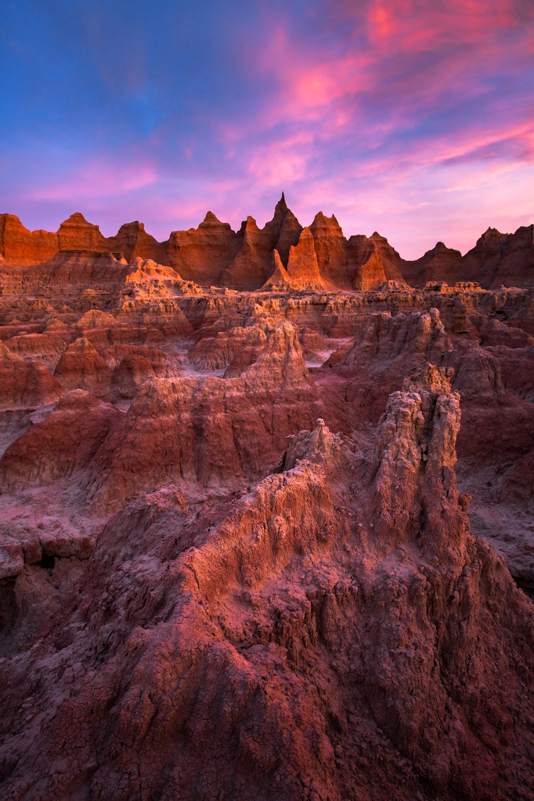The jagged peaks of the Badlands rise from the prairie like an unpassable wall of stone and rock illuminated by the rising sun...
