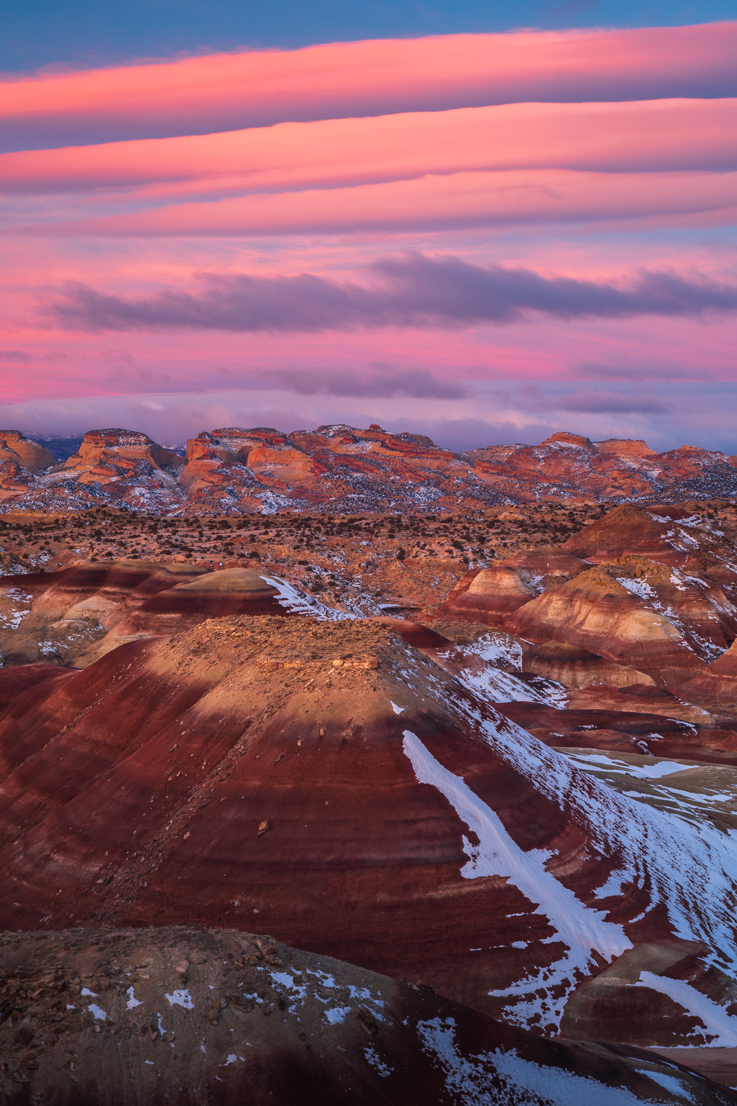 Bentonite Badlands before the Capitol Domes of Capitol Reef National Park at sunrise.